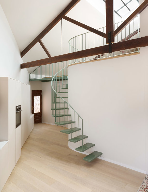 Todo gira alrededor de la escalera verde que sube al altillo en esta casa de estilo industrial