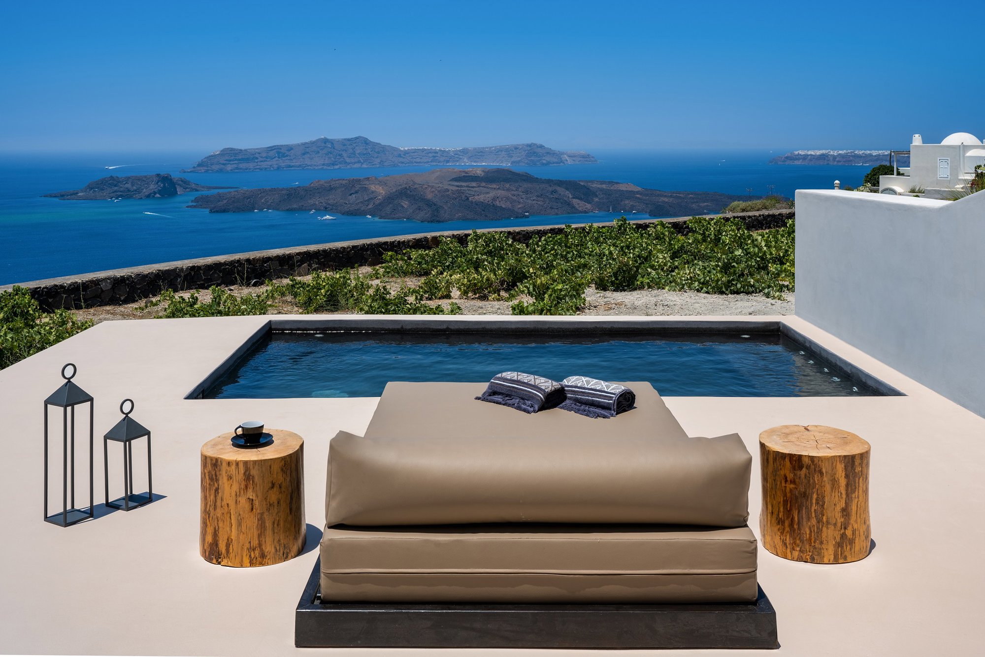 Una piscina en Grecia del mismo color del mar con una terraza de color arena.