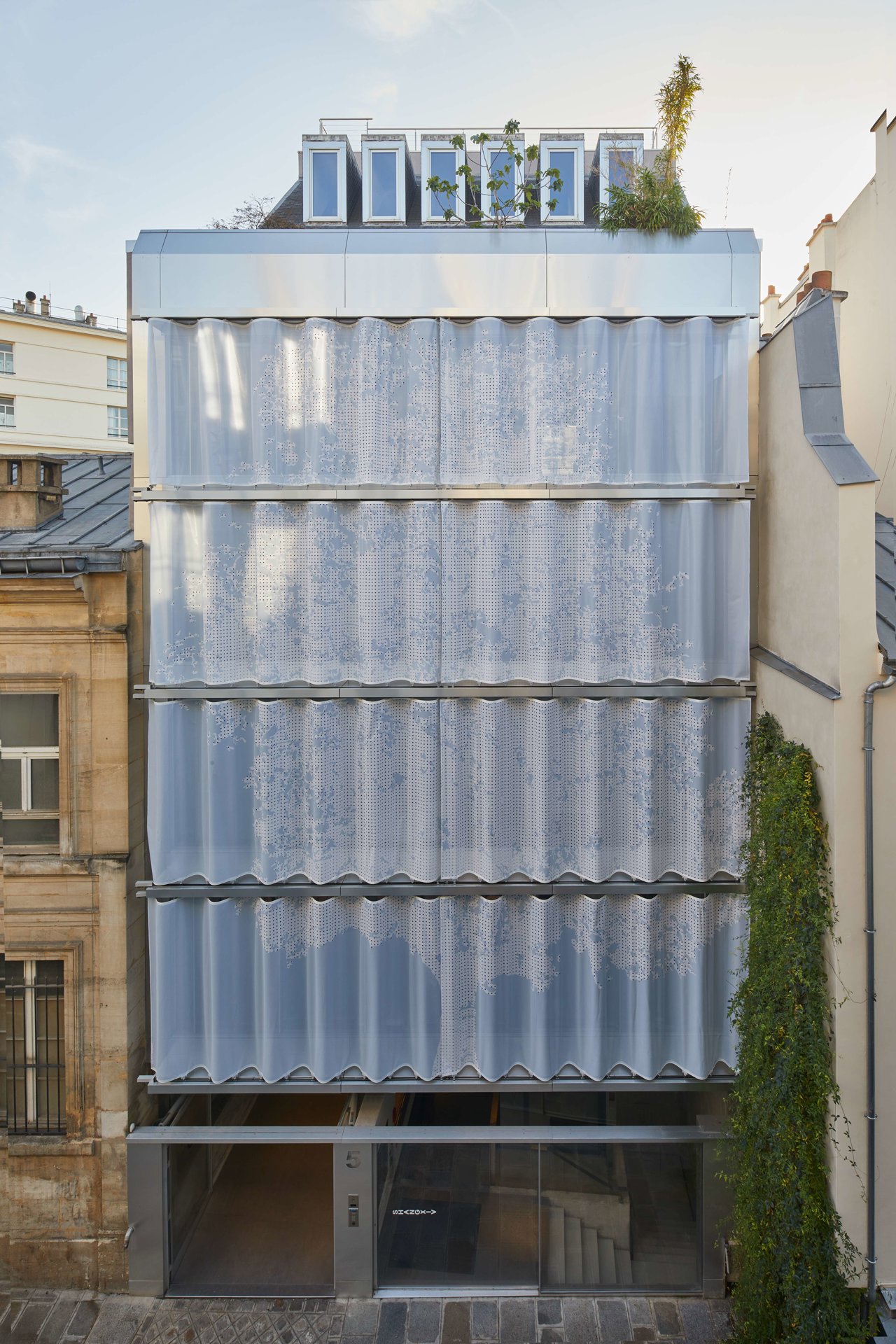 La silueta de un pruno se intuye en la cortina de 10 m que cubre la fachada de un edificio de los años setenta en la parisina Rue du Vertbois, de Inside Outside con Moussafir Architectes.