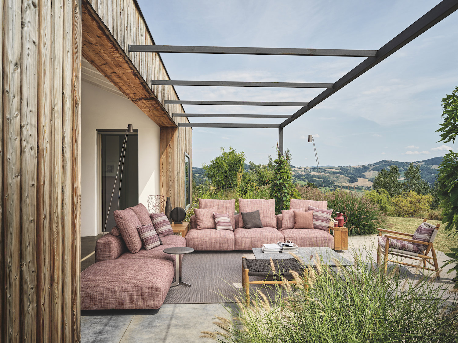 POrche de una casa moderna en el campo con sofas de color rosa