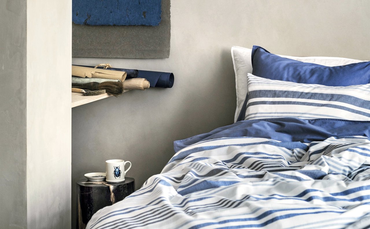 Dormitorio gris y azul con sábanas de rayas marineras