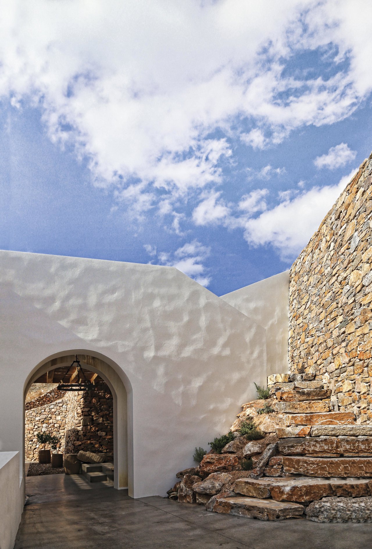Muros encalados rugosos y de piedra seca definen el exterior de la casa Syros II, de Black722
