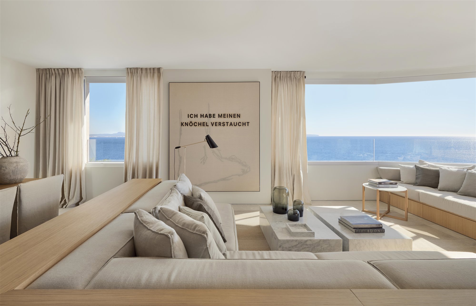 salón minimalista con vistas al mar sofá banco de madera y color blanco roto