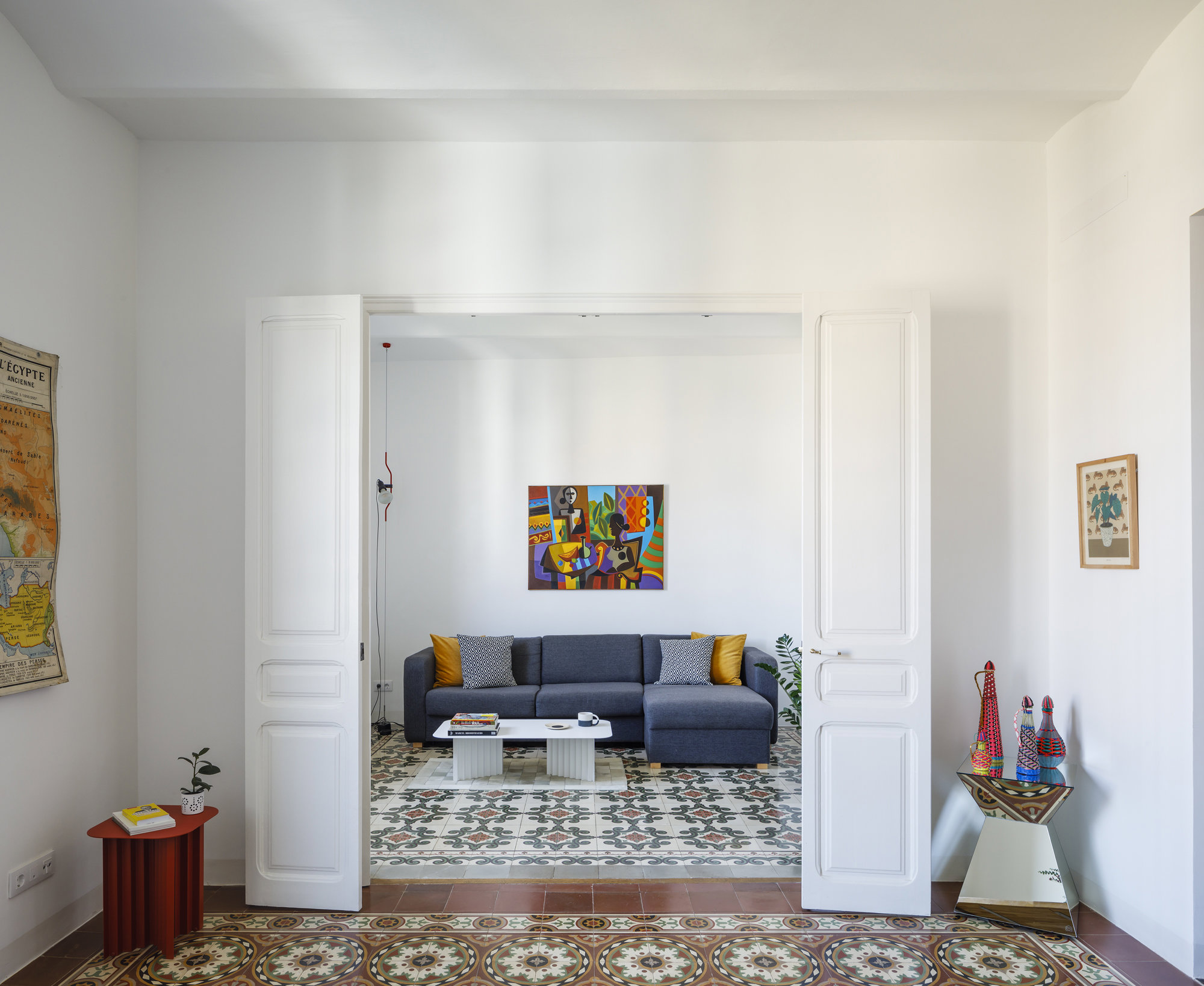 Salon con sofa de color azul y puertas de color blanco  de un piso en Barcelona