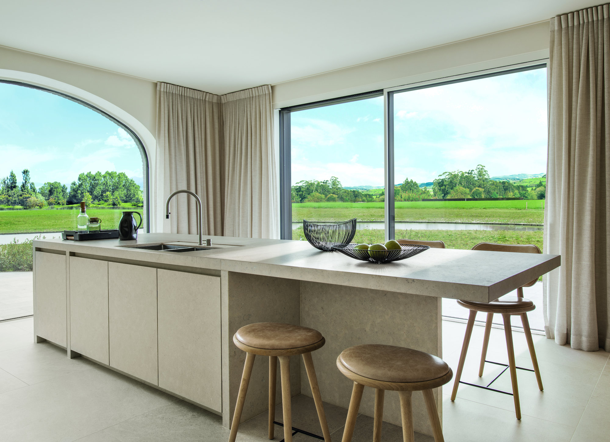 Cocina moderna con isla y grandes ventanales con vistas al exterior. 