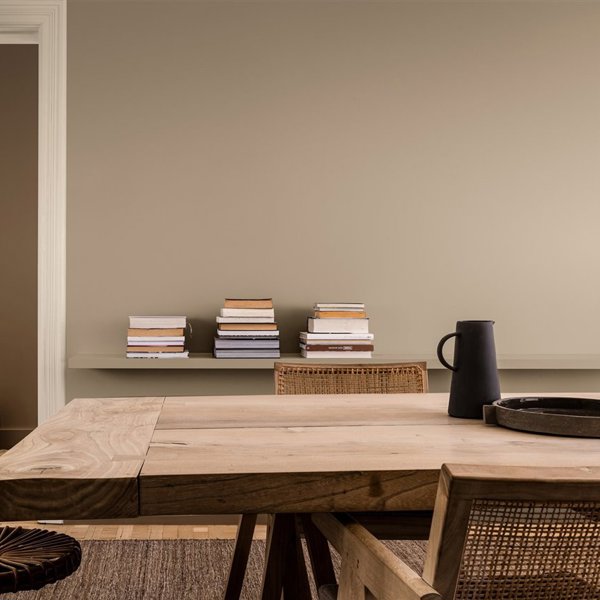 Salon con mesa de madera y libros paredes en color beige