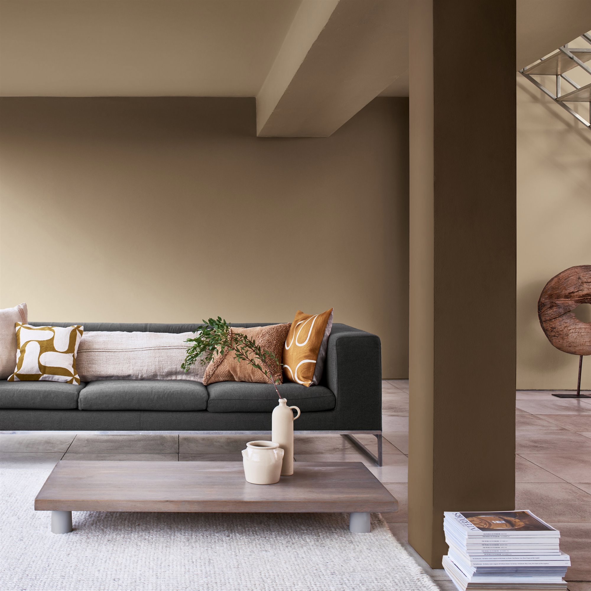 Salon con sofa gris y paredes en color beige y marron