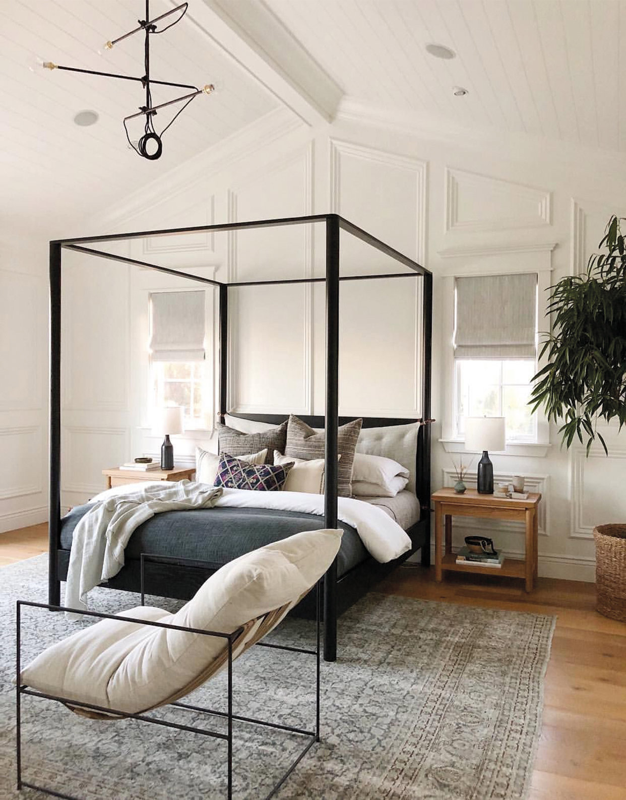dormitorio moderno cama con dosel negro, alfombra, butaca