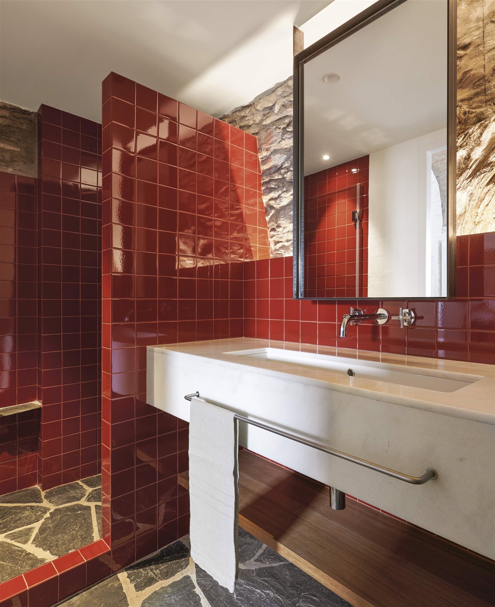 Baño con azulejos rojos en acabado brillo.