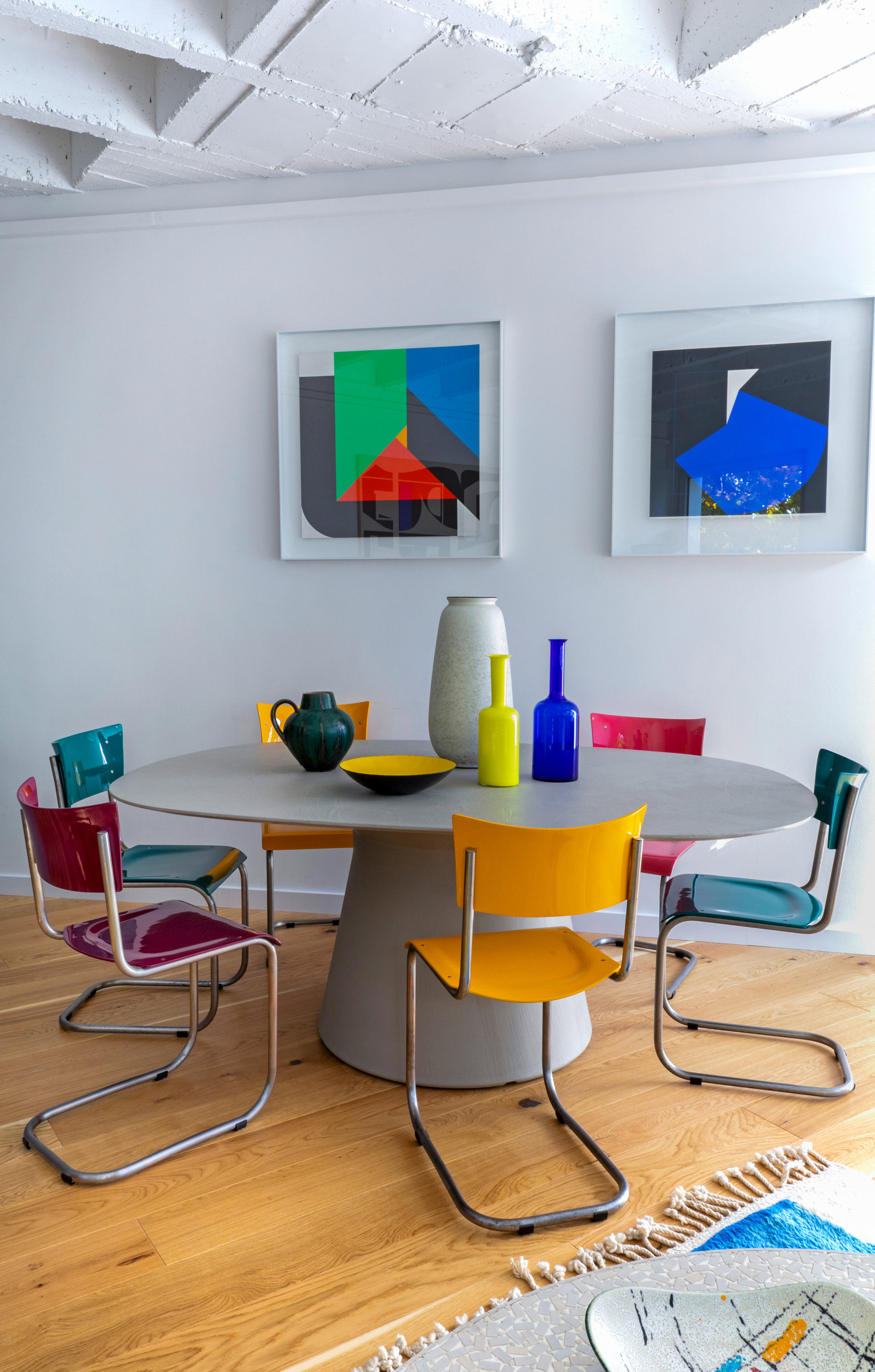 Comedor con mesa gris redonda y sillas de colores. 