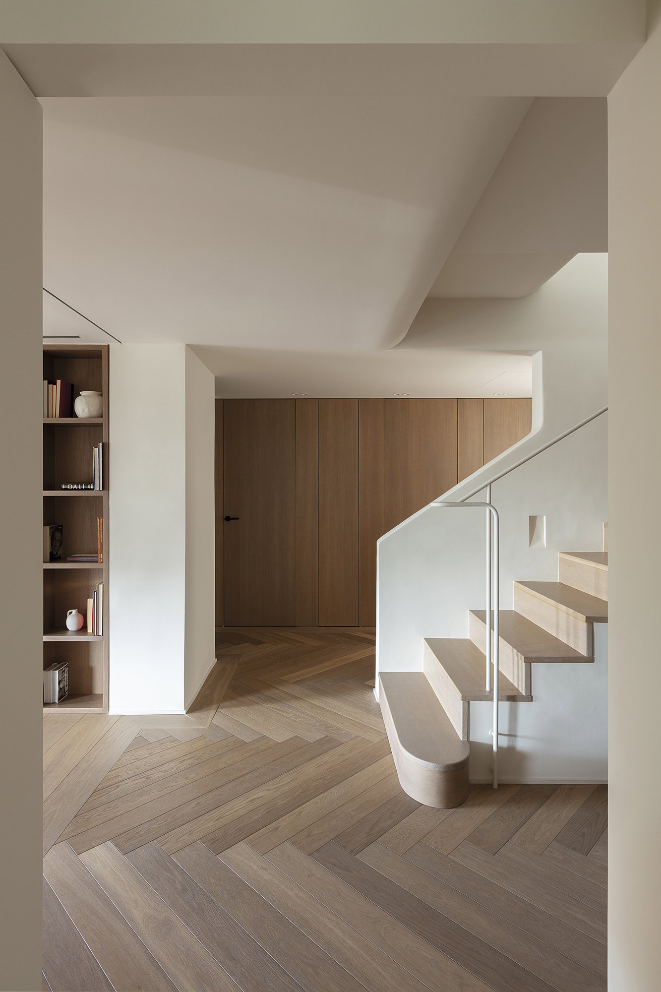 Distribuidor con escalera blanca y suelos de madera.