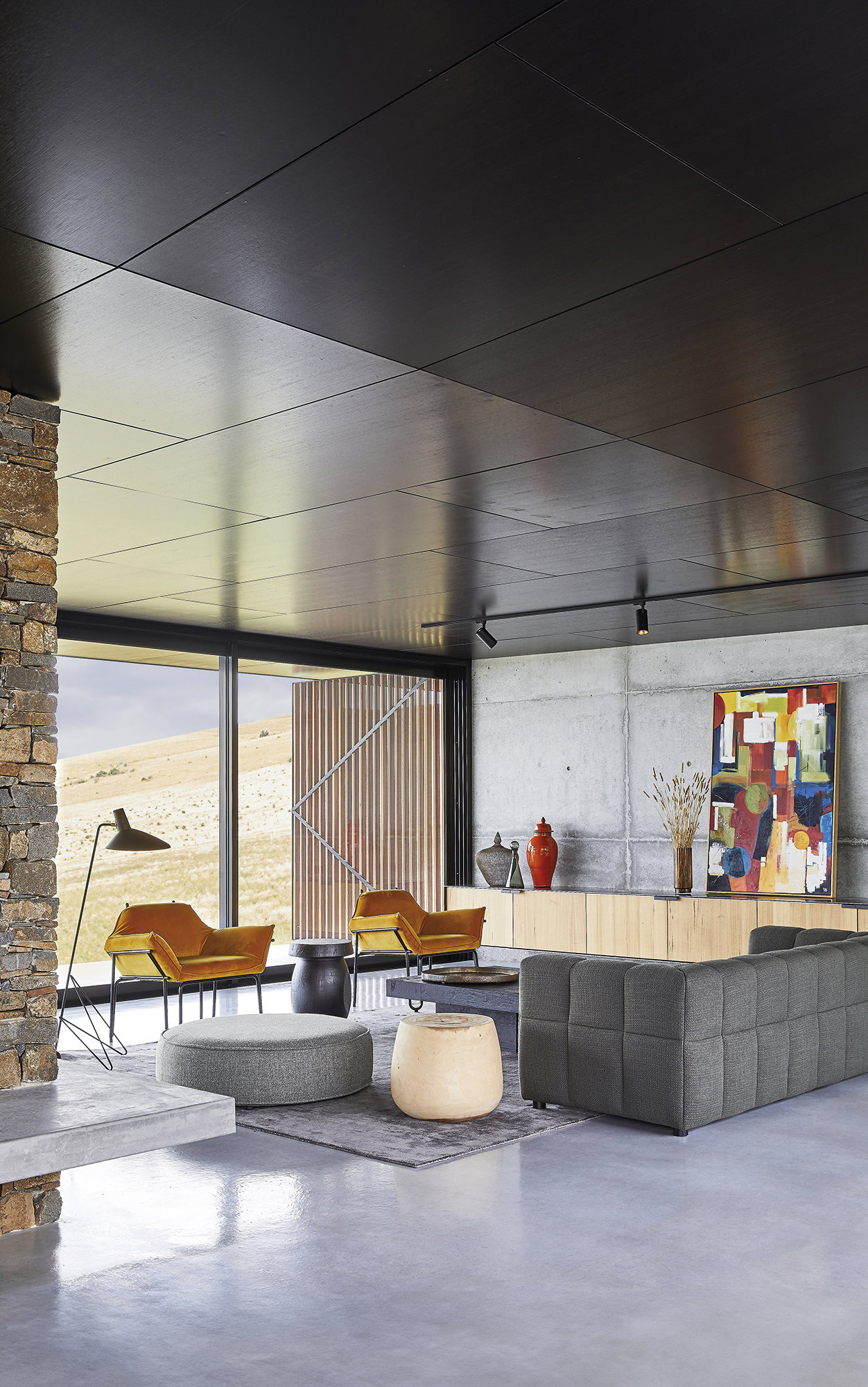 Salón moderno con sofá gris y butacas amarillas.