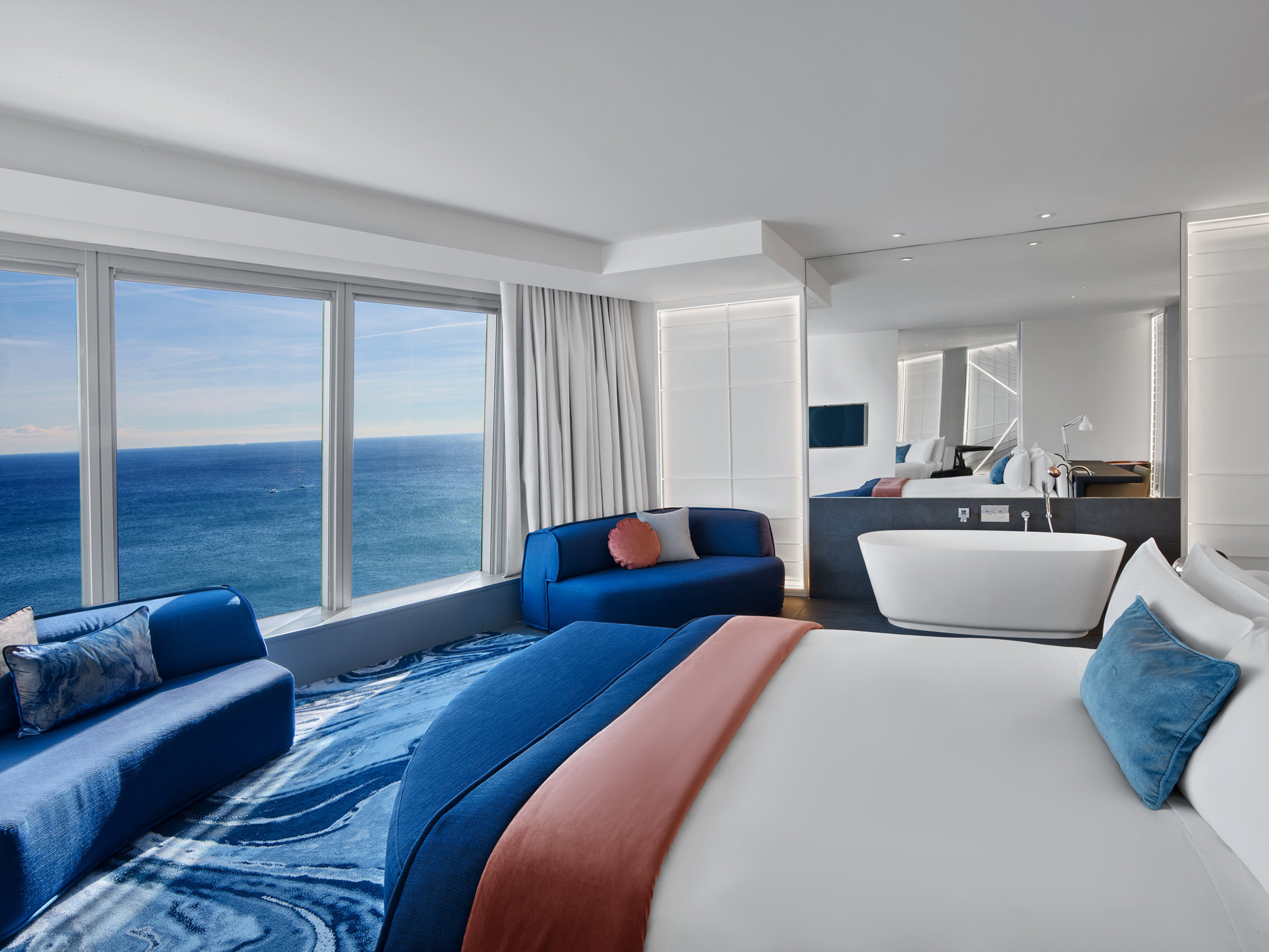 Dormitorio moderno con bañera y sofás azules. 