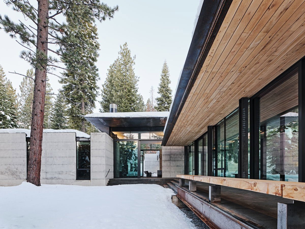 Exterior de una cabaña en el bosque rodeada de nieve.