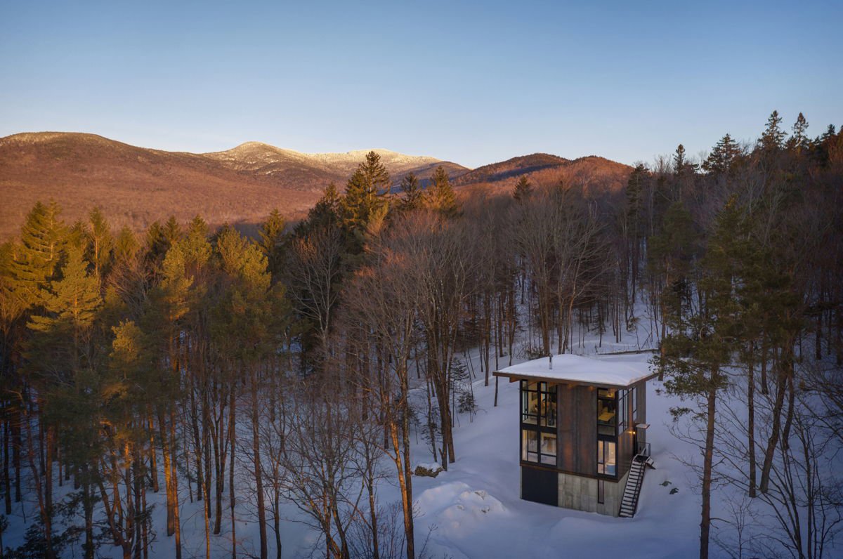 Cabaña en el bosque rodeada de nieve.
