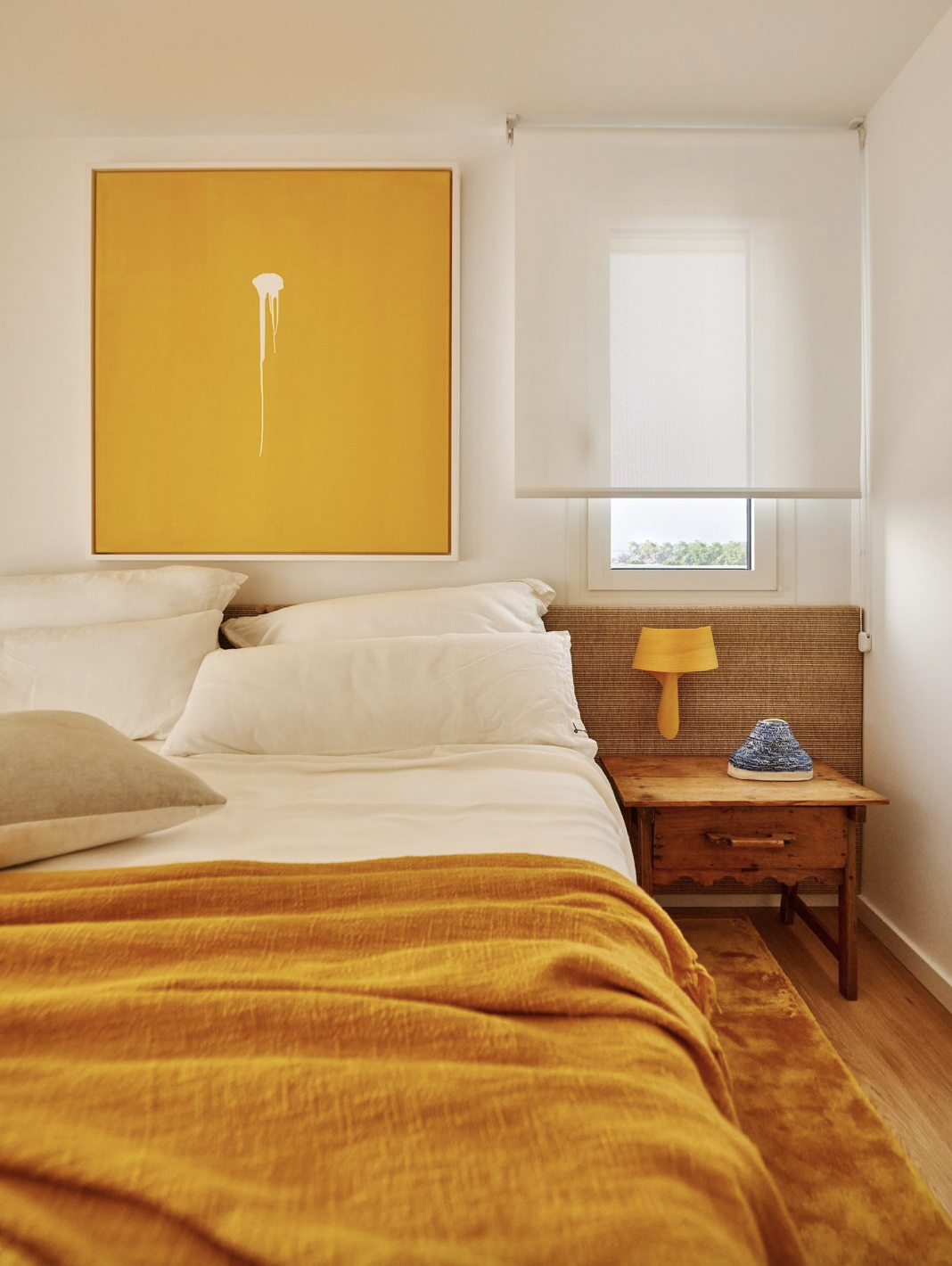 Dormitorio con cuadro y ropa de cama amarillos. 