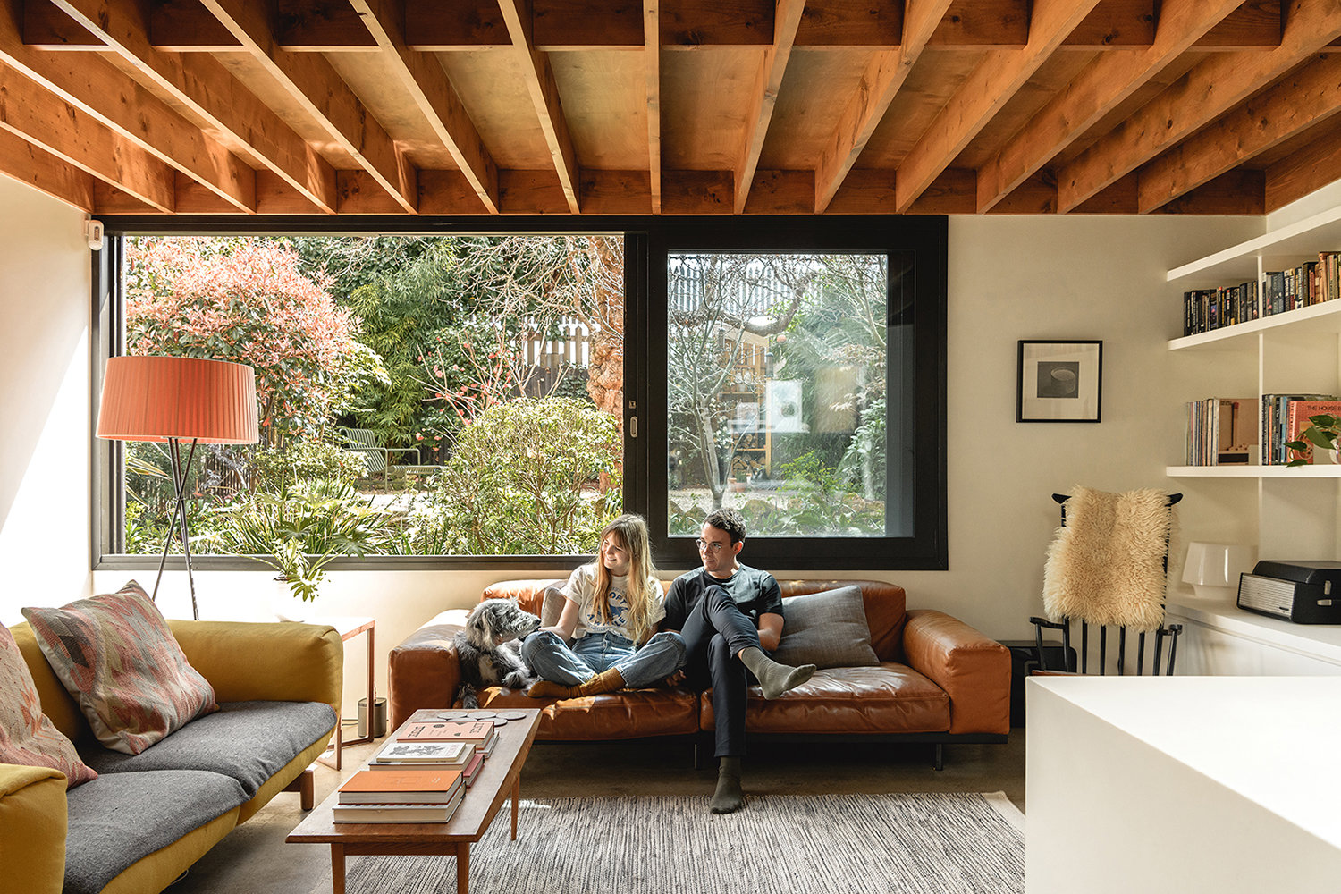 pareja sentada en sofá de cuero en salón cn techo con vigas de madera