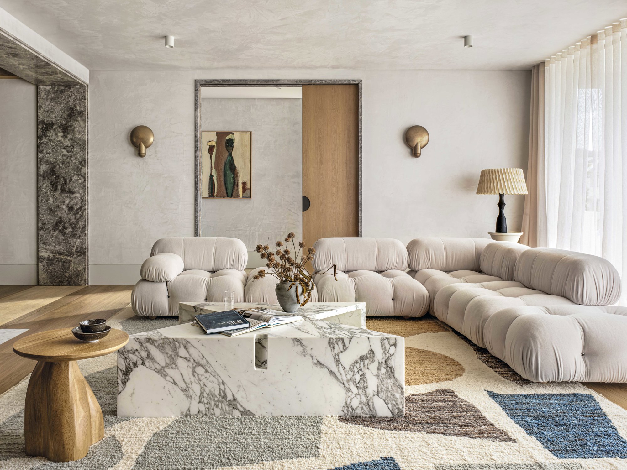 Salon con sofa de lineas curvas, mesa de marmol y alfombra