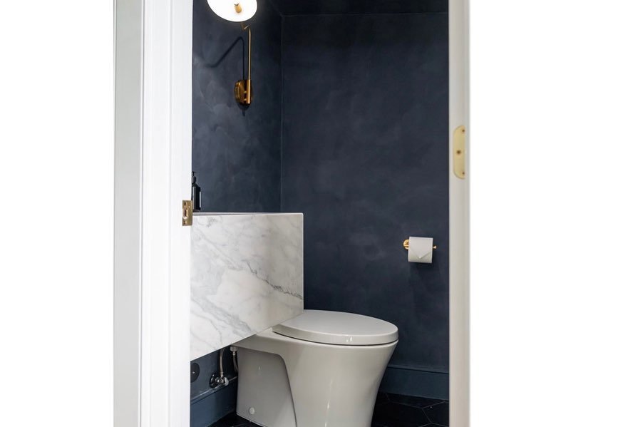 baño con paredes azul oscuro y detalles dorados.