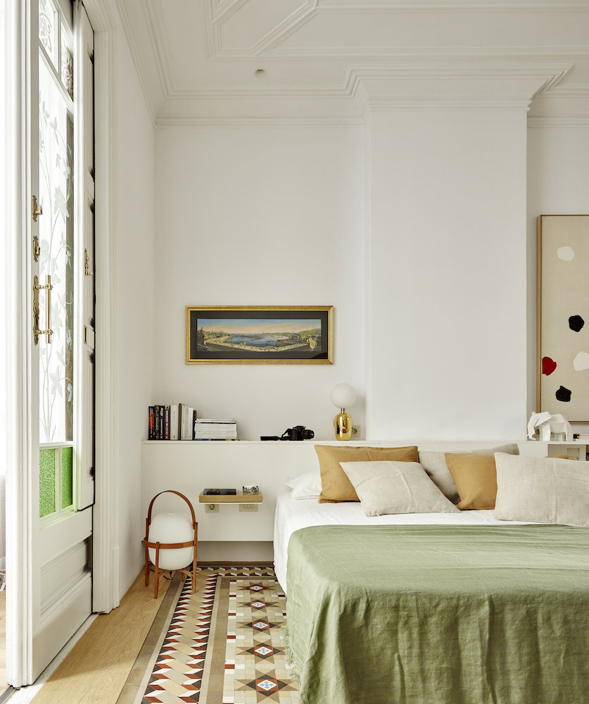 Dormitorio con suelo hidráulico con ropa de cama verde y blanca.