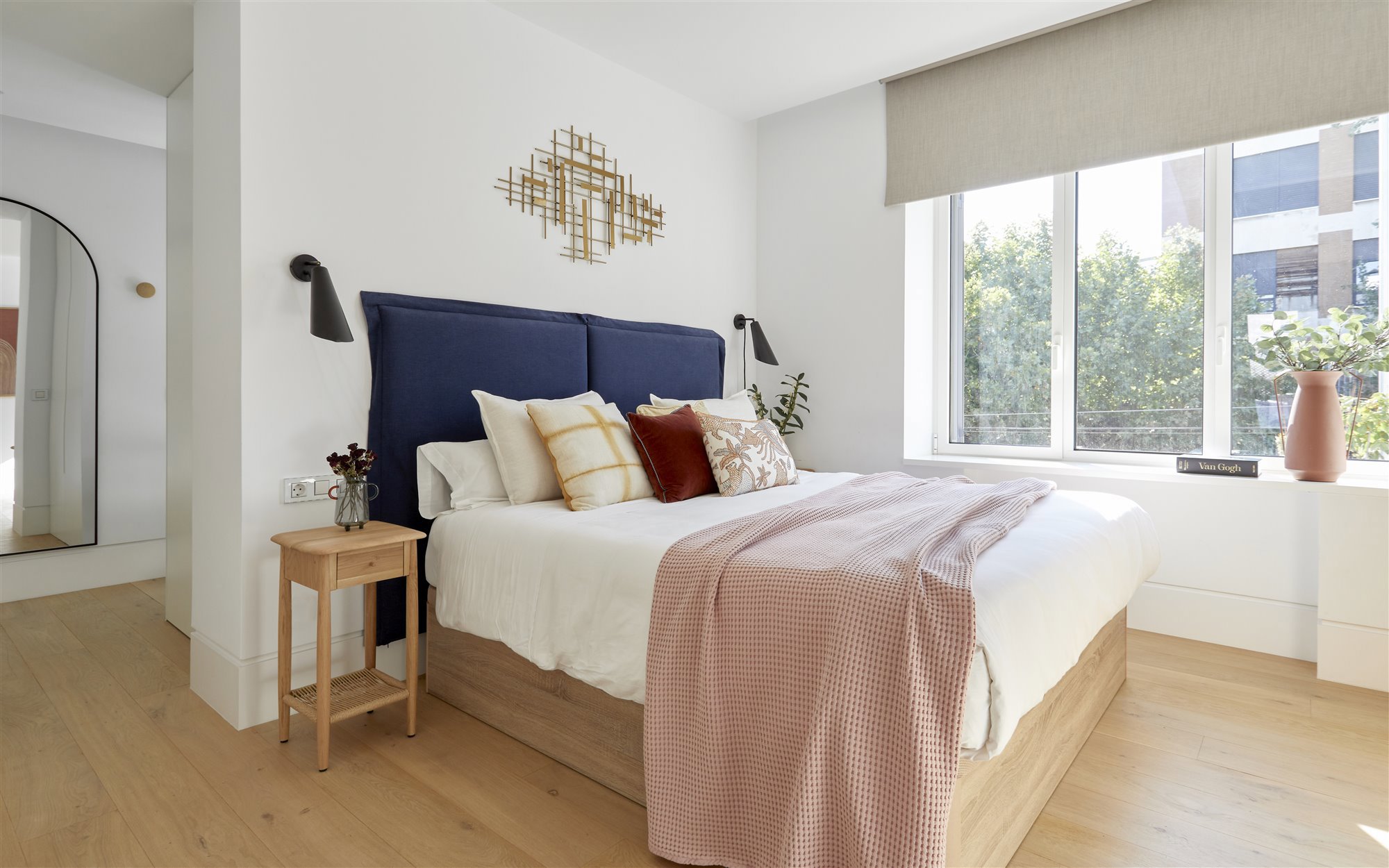 Dormitorio con cabecero tapizado y ropa de cama blanca y rosa. 