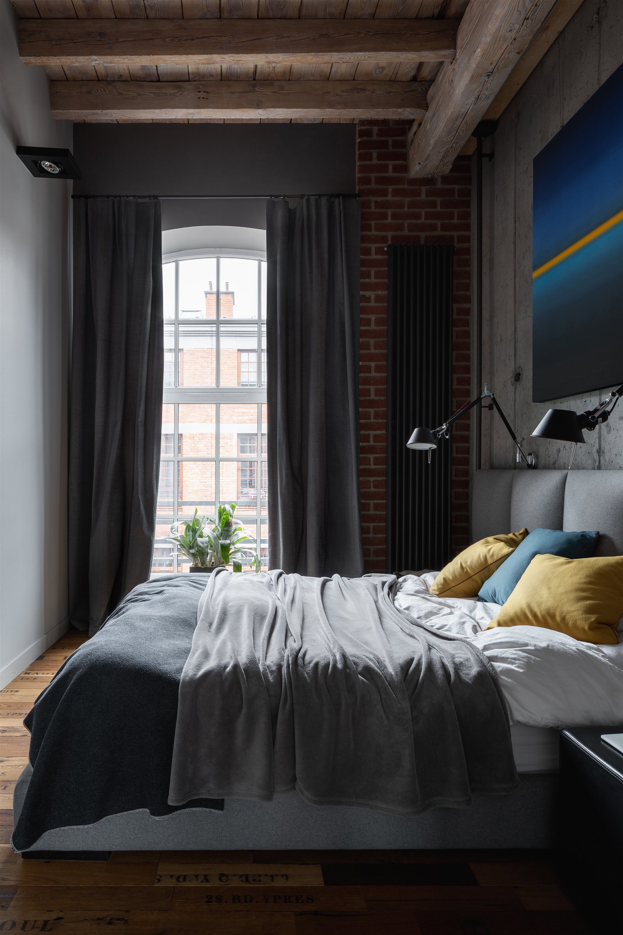Dormitorio con ventana de suelo a techo y ropa de cama gris.