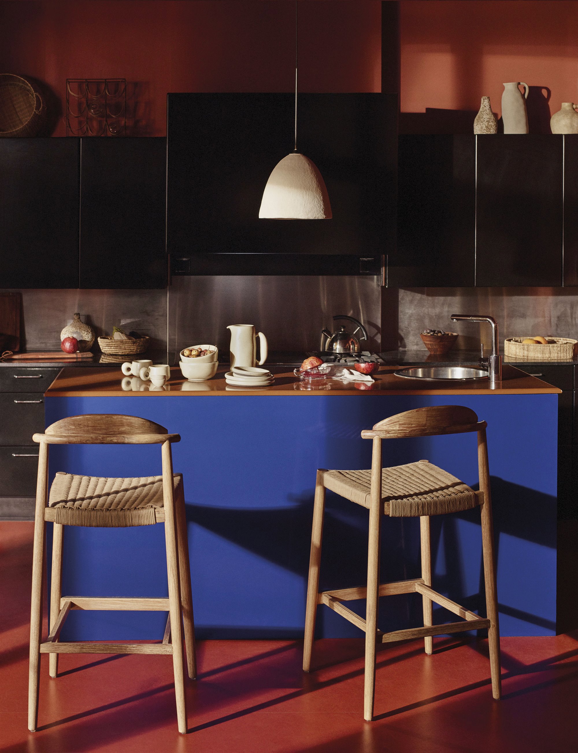 cocina de la casa de Leopoldo Pomes en azul, negro y suelo rojo, con butacas