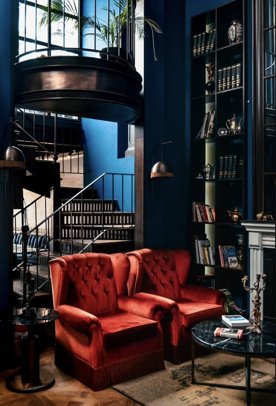 salon con dos butacas rojas, paredes azules, una escalera y chimenea