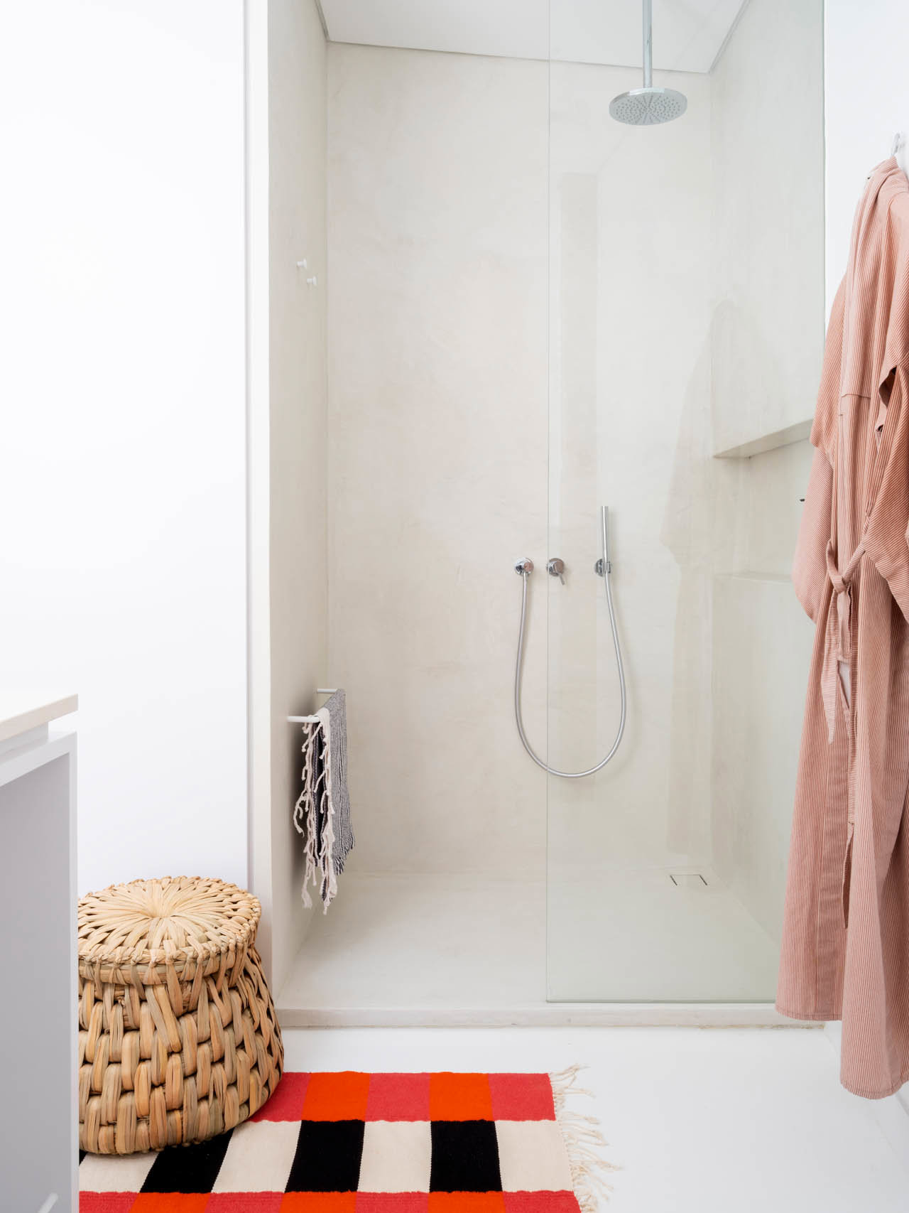 Baño con ducha encastrada y alfombra de diseño.
