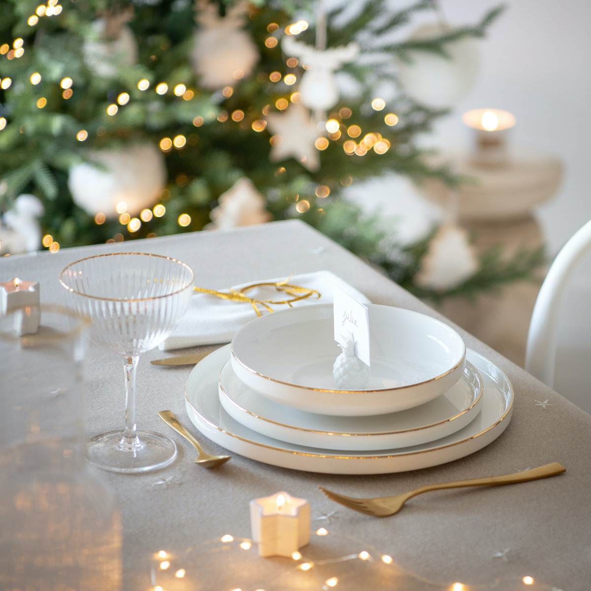 Mesa de navidad con decoración en color dorado y mantel blanco