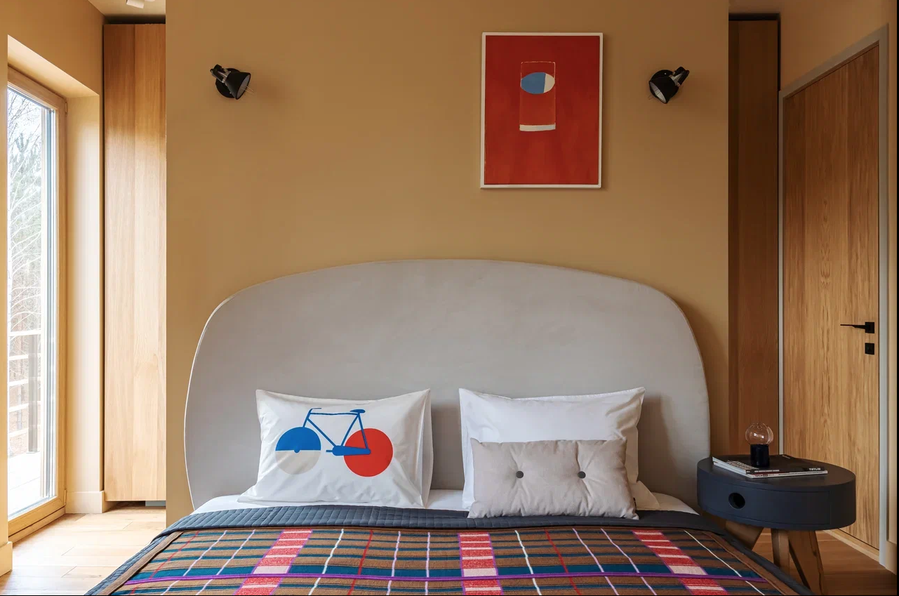 Dormitorio con cabecero tapizado, pared con aploques y manta. decuadros.