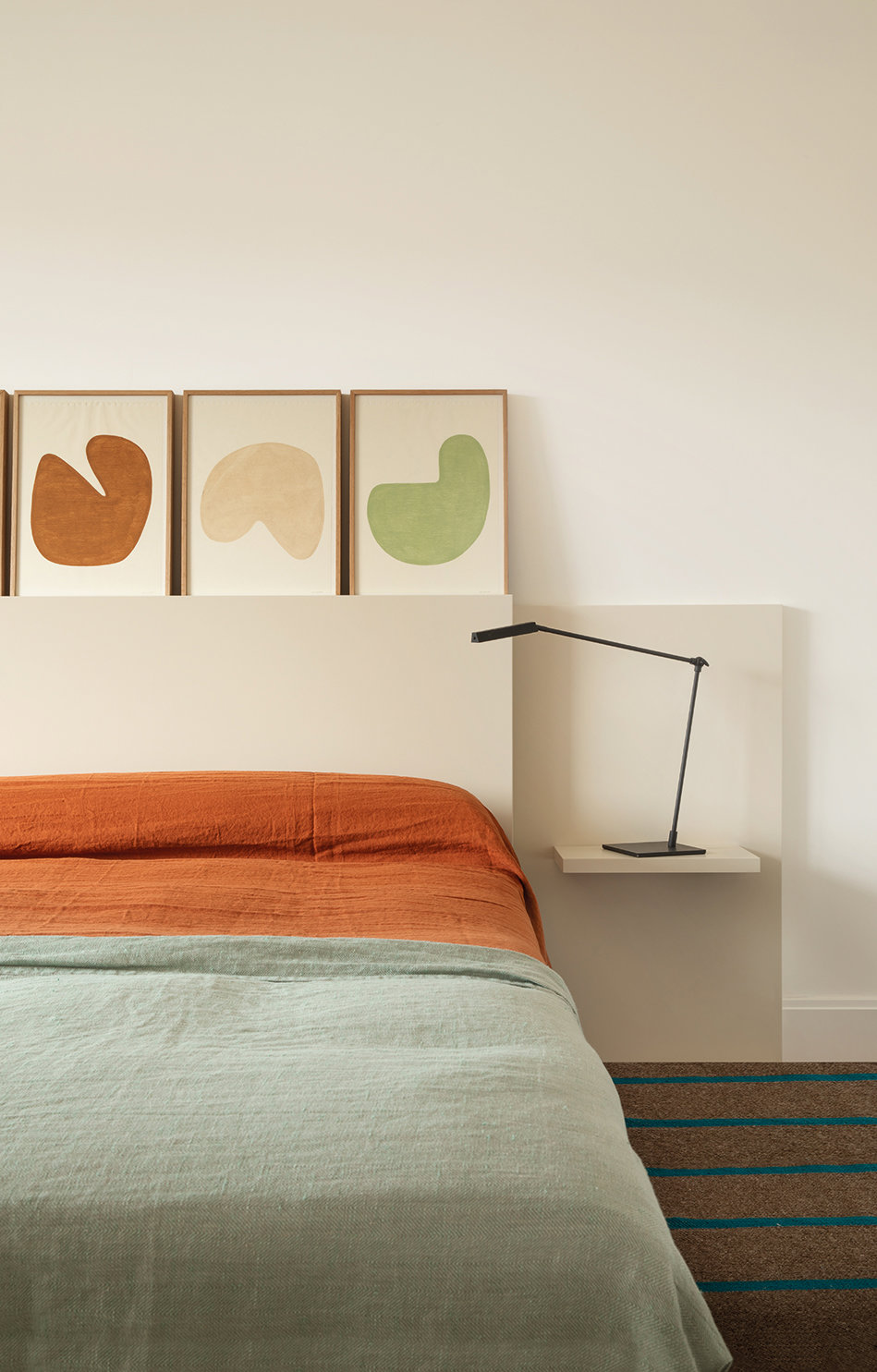 Dormitorio con cama con ropa de cama color naranja y verde. 
