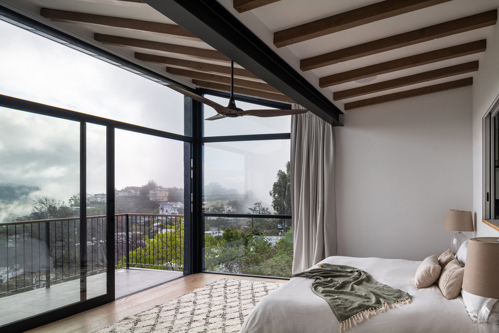 Dormitorio con amplios ventanales y vistas a las colinas