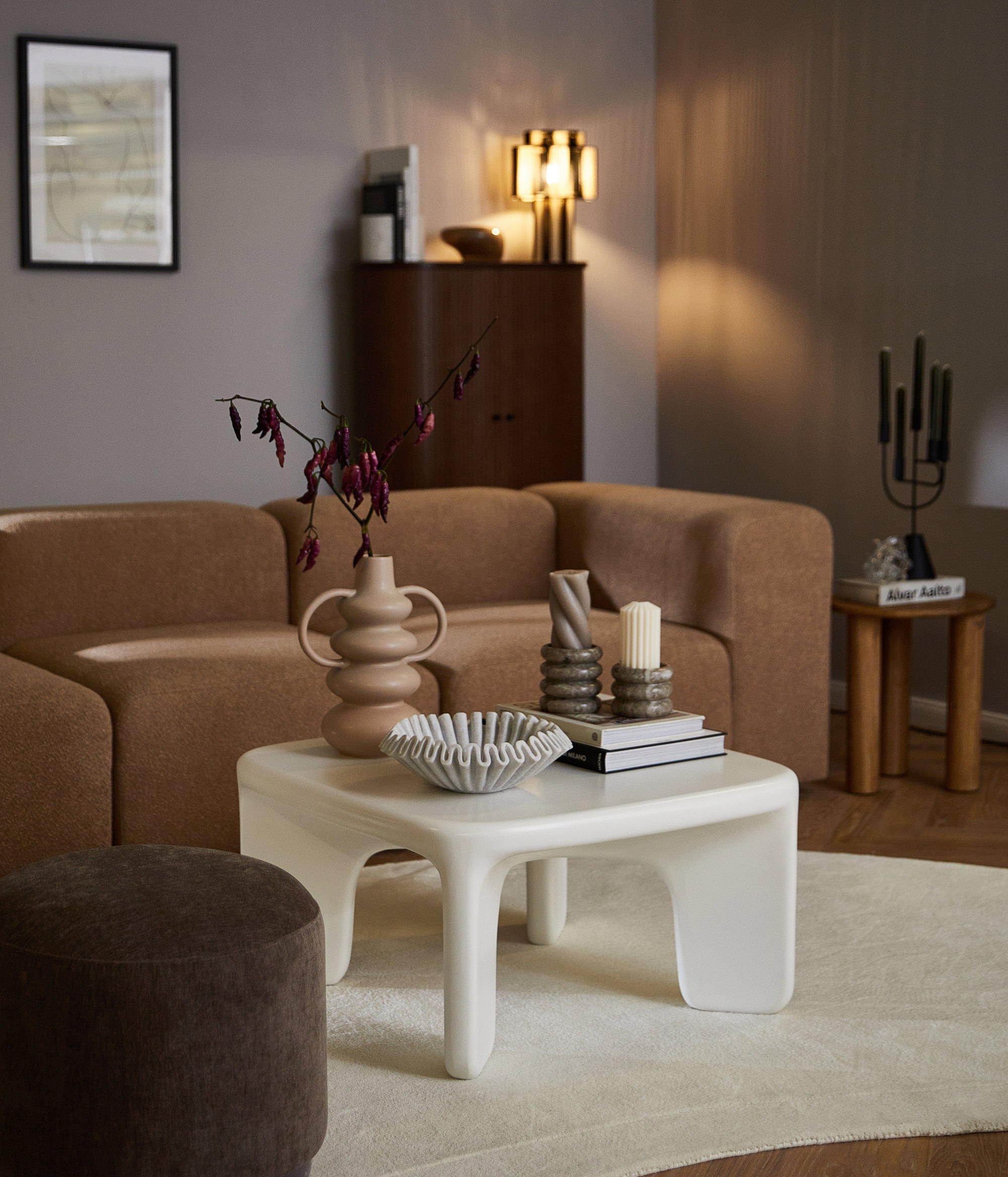 Formas orgánicas en un salón con mesa de centro blanca y sofá marrón